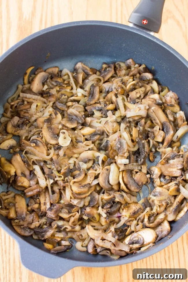 Close-up of golden-brown sautéed mushrooms, perfectly cooked and ready to be layered into the Salmon Coulibiac.