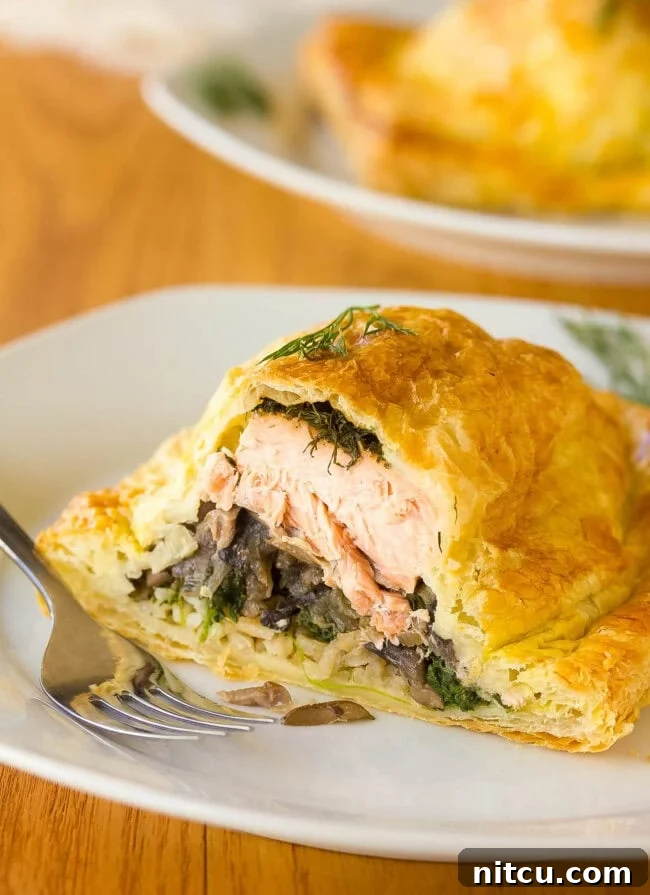 A stunning Holiday Salmon Wellington (Salmon en Croûte) sliced open to artfully display its rich, layered interior of salmon, rice, and vegetables.