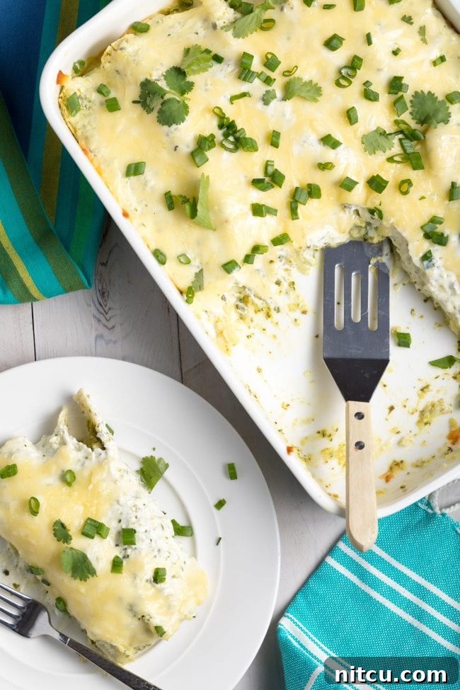 Enchiladas Suizas in a baking dish with a piece removed, revealing the delicious layers.