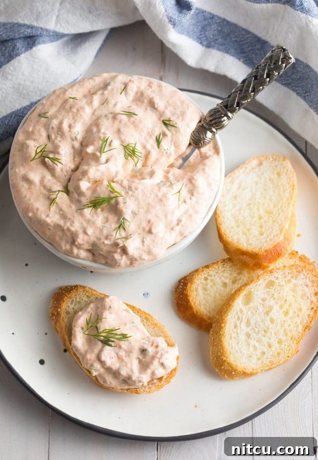 Crisp toasted baguette slices generously topped with creamy smoked salmon dip, ready to be enjoyed.