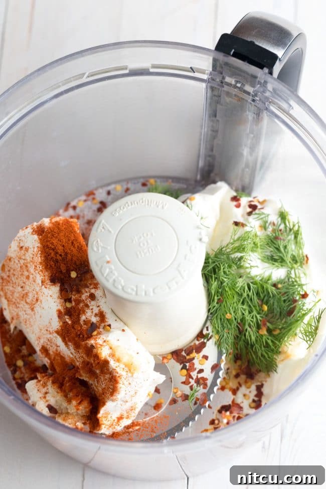Half of the essential ingredients, including creamy components and aromatic spices, arranged in a food processor, ready for blending.
