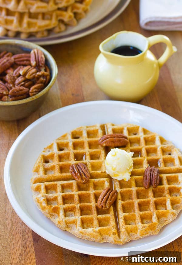 Crispy Spelt Waffles, beautifully golden, stacked on a plate with fresh fruit.