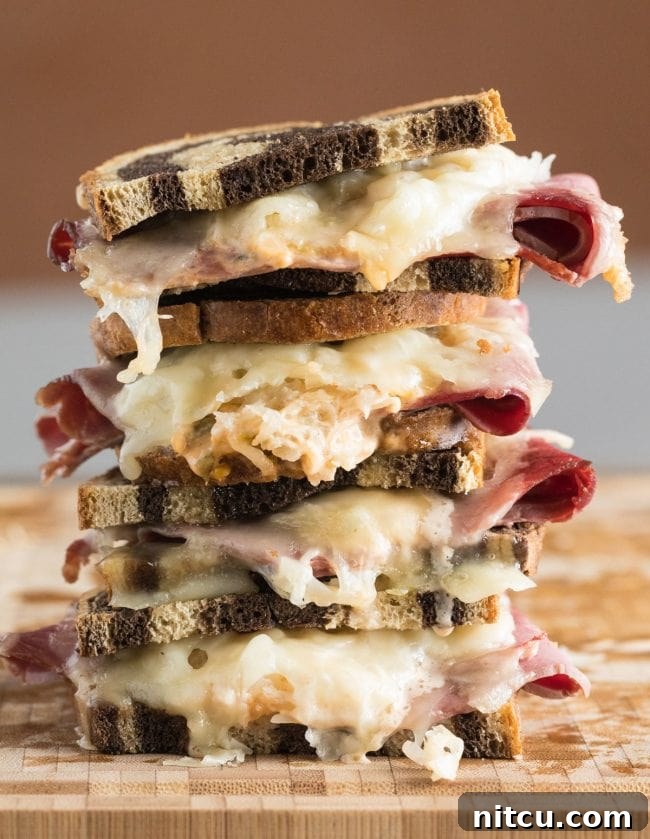 Reuben sandwiches stacked on top of each other, showcasing crispy bread and melted cheese.