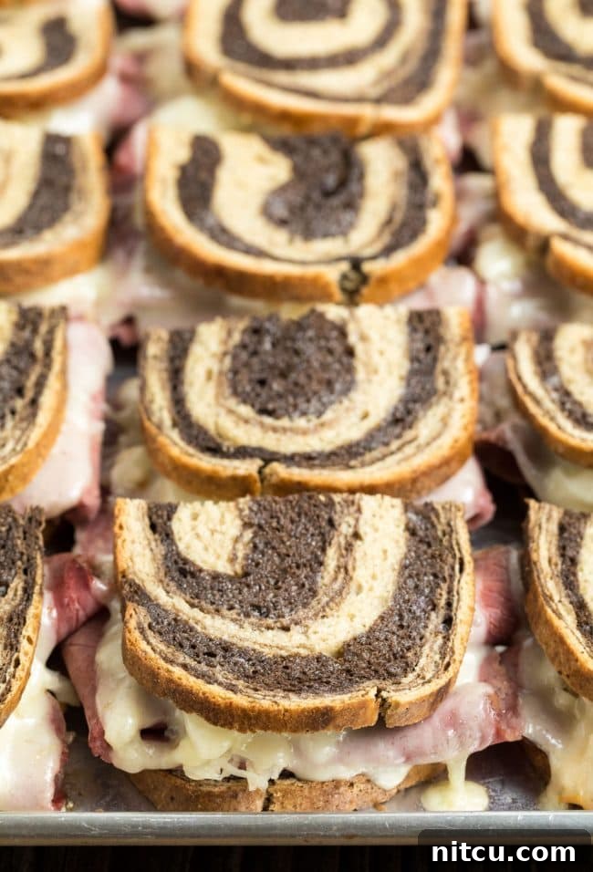 Oven Baked Reuben Sandwiches neatly lined up on a sheet pan, ready to be served.