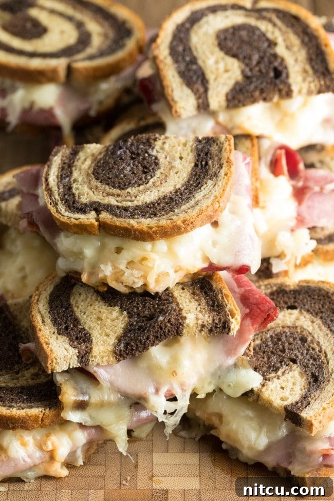 Baked Reuben sandwiches, beautifully stacked on a wooden background, highlighting their delicious layers.