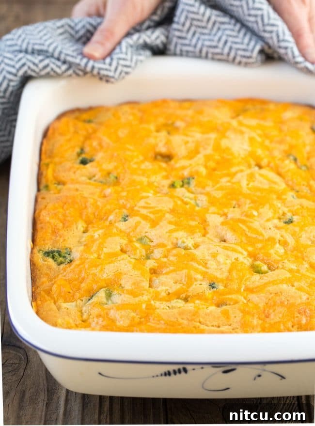 Close-up of a square of fluffy broccoli cornbread with melted cheese