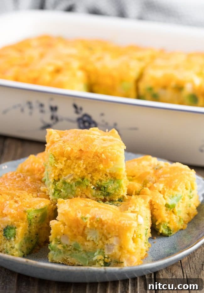 Fluffy Broccoli Cheese Cornbread squares neatly stacked on a blue plate