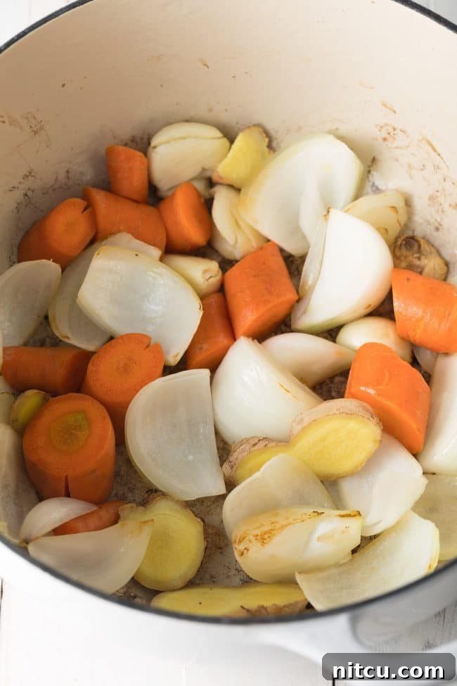 Carrots, onions, garlic and ginger being sautéed in a large stock pot.