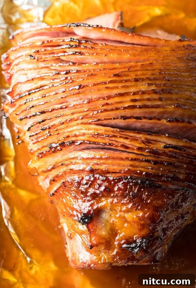 Overhead shot of a ham, partially covered in foil, absorbing the Coca-Cola glaze during baking.