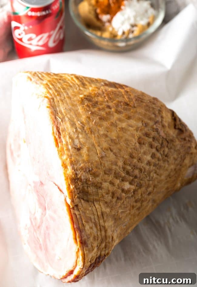 A spiral-cut ham resting on a baking sheet, displaying its natural grooves before the glaze is applied.
