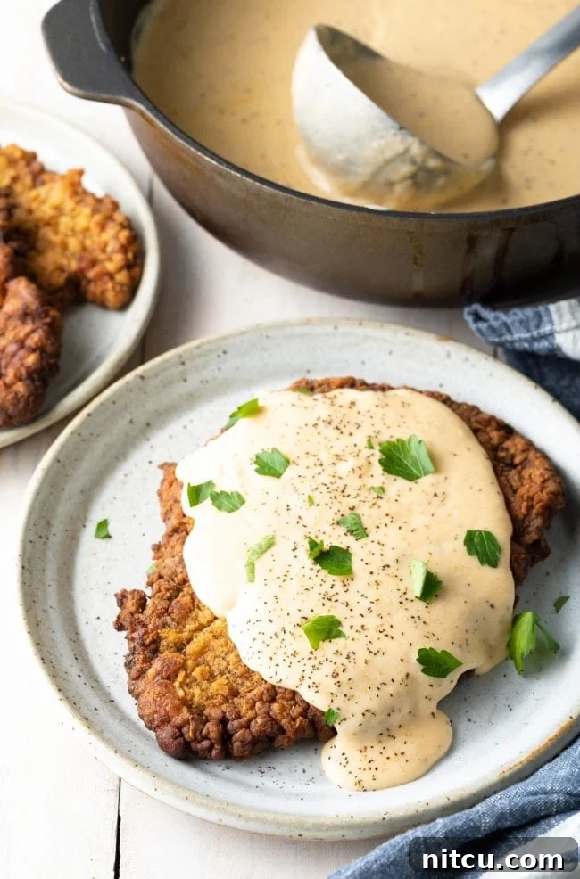 Best Chicken Fried Steak Recipe: A perfectly golden-brown, crispy chicken fried steak topped with a generous dollop of creamy white gravy, ready to be served as a classic Southern comfort meal.