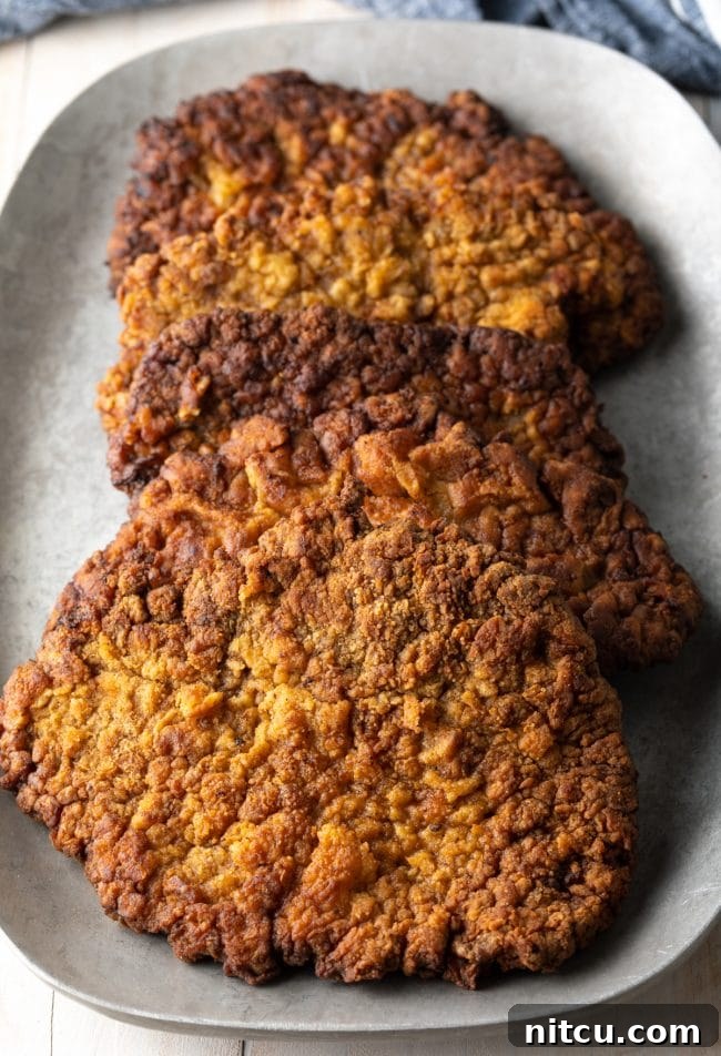 Country Fried Steak: A close-up shot of a golden-brown, crispy country fried steak, showcasing its textured breading and inviting appearance before gravy is added.