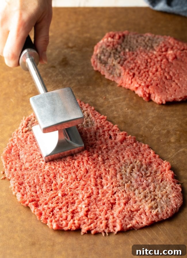 Cube Steak: A piece of tenderized cube steak, ready for breading and frying, showing its characteristic textured surface.