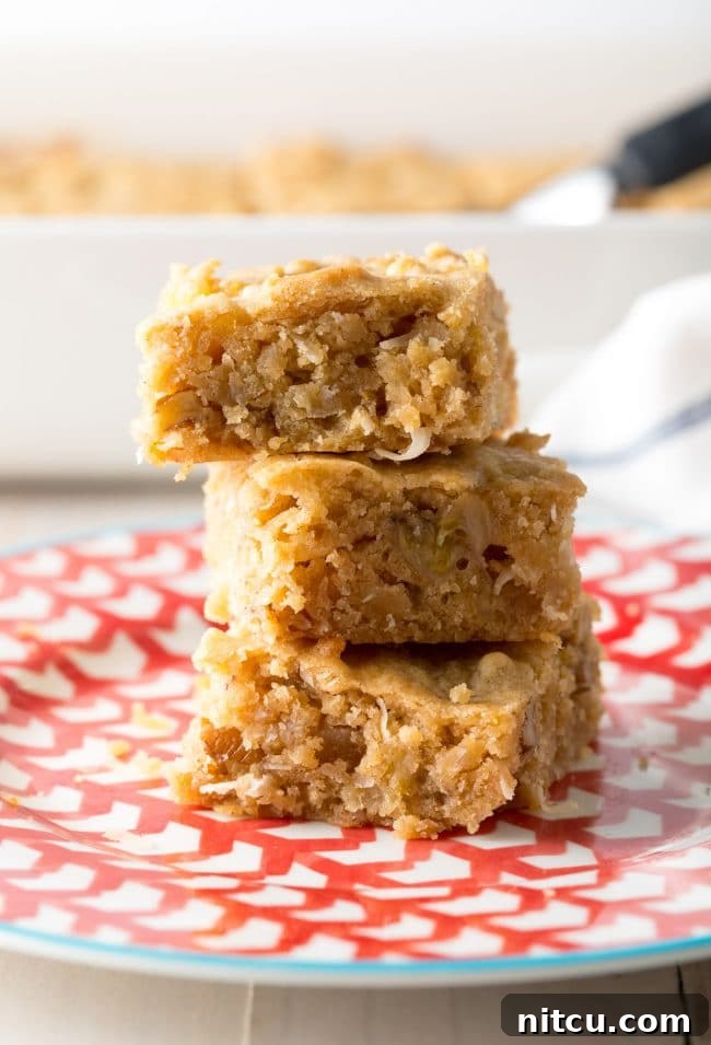 A stack of golden-brown blondie cookie bars arranged invitingly on a white plate.
