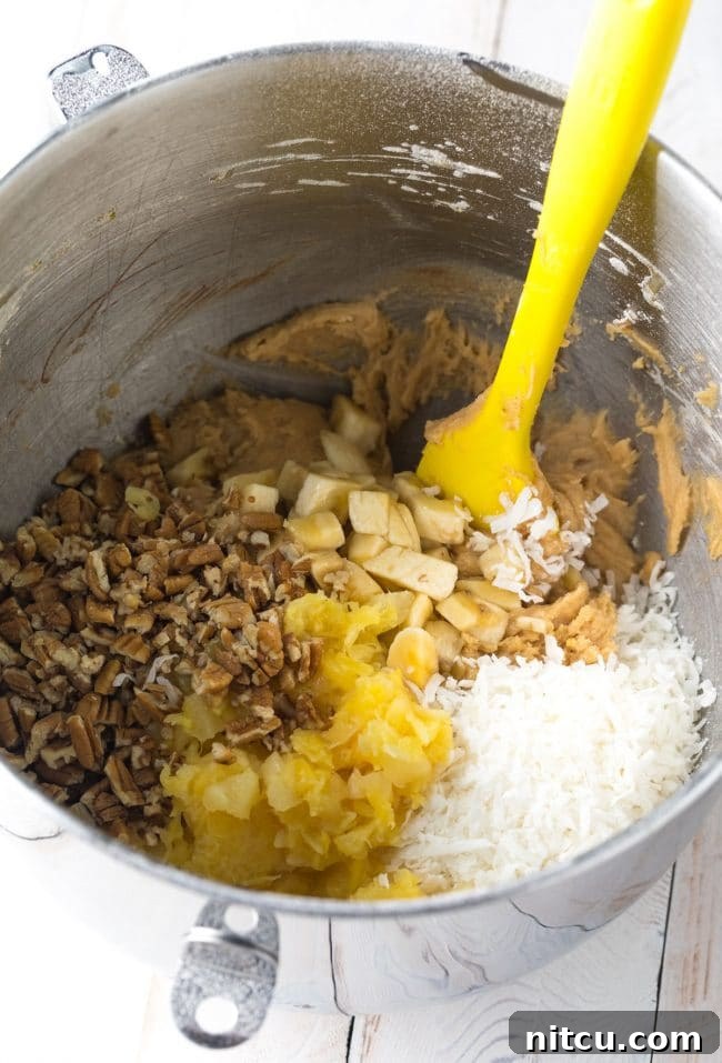 Ingredients for hummingbird blondies being mixed in a large bowl, showing the vibrant mix of fruit and nuts.