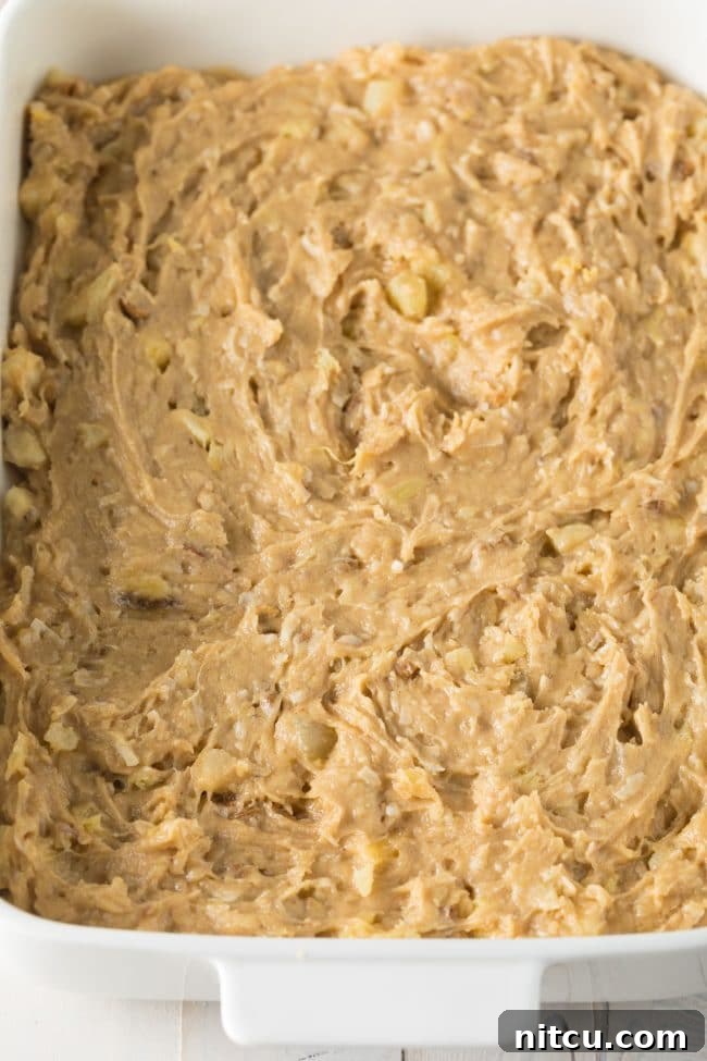 Golden blondie cookie dough expertly spread into a baking dish, ready for the oven.