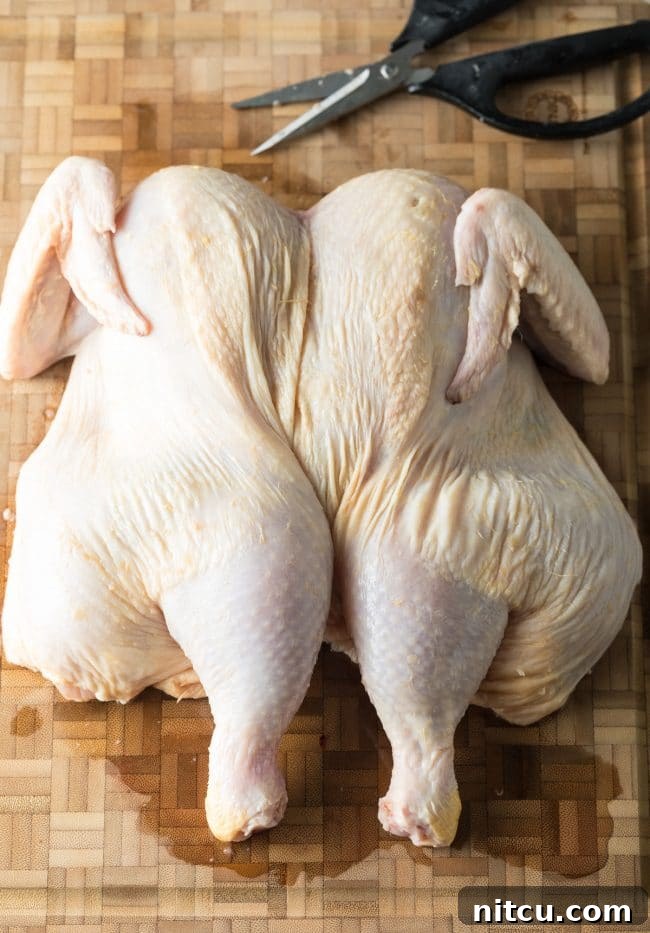 Finished spatchcocked chicken laid flat on cutting board.
