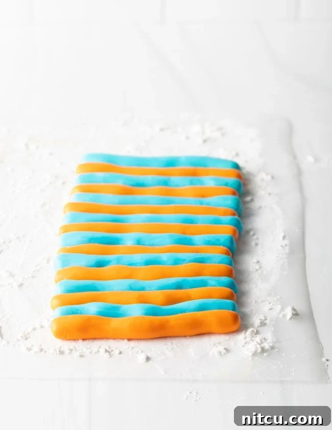Orange and blue striped fondant being prepped to be rolled out. 