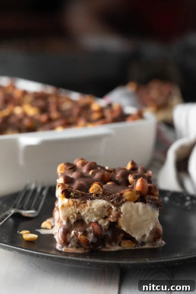 A perfect slice of buster bar ice cream cake served on a elegant black plate, showing its distinct layers.