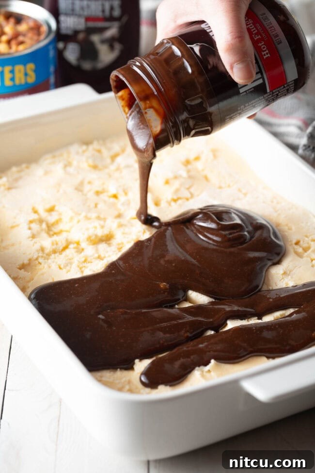 Hot fudge sauce being poured over the first ice cream layer.