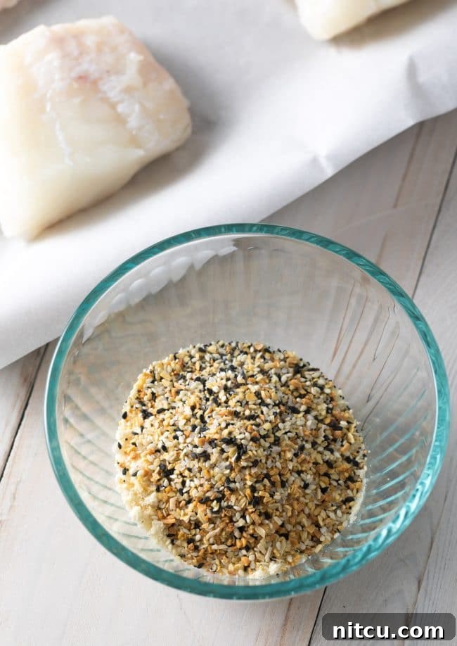 Raw white fish next to a small bowl of everything bagel seasoning. 