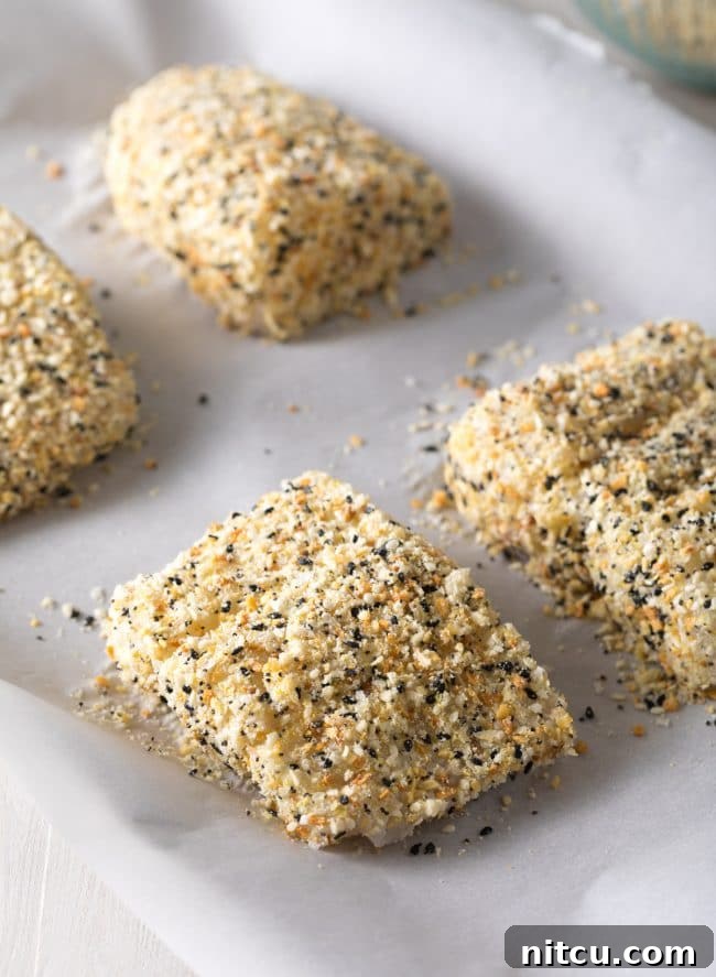 Raw white fish on a baking dish with an everything bagel seasoning crust. 