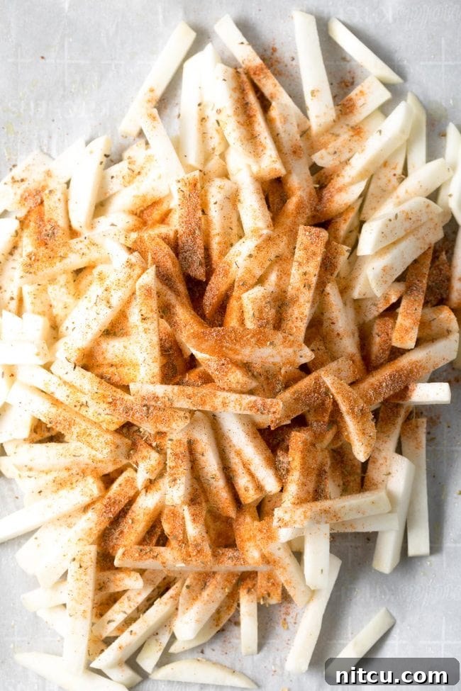 Freshly baked turnip fries spread out on a baking sheet, showing their golden brown and crispy texture.