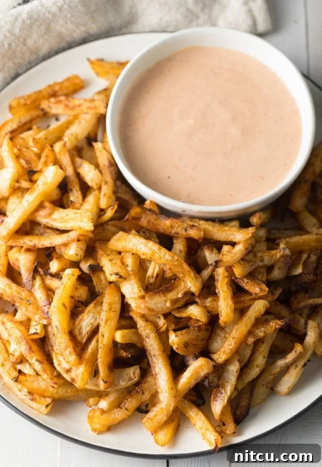 Crispy Air Fryer Turnip Fries served on a plate with a side of dipping sauce, showing a perfectly cooked batch.