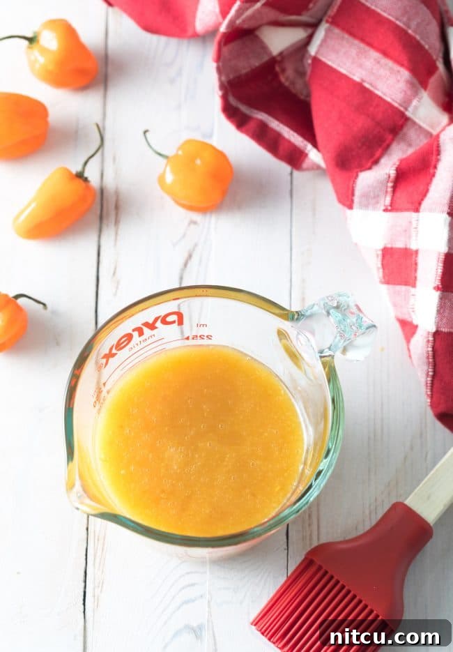 Glass mixing pitcher of peach habanero wing sauce.