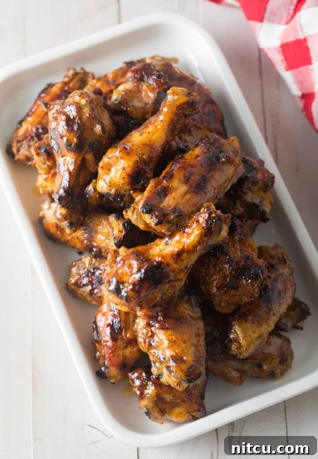 White rectangle dish brimming with glazed grilled habanero peach chicken wings.