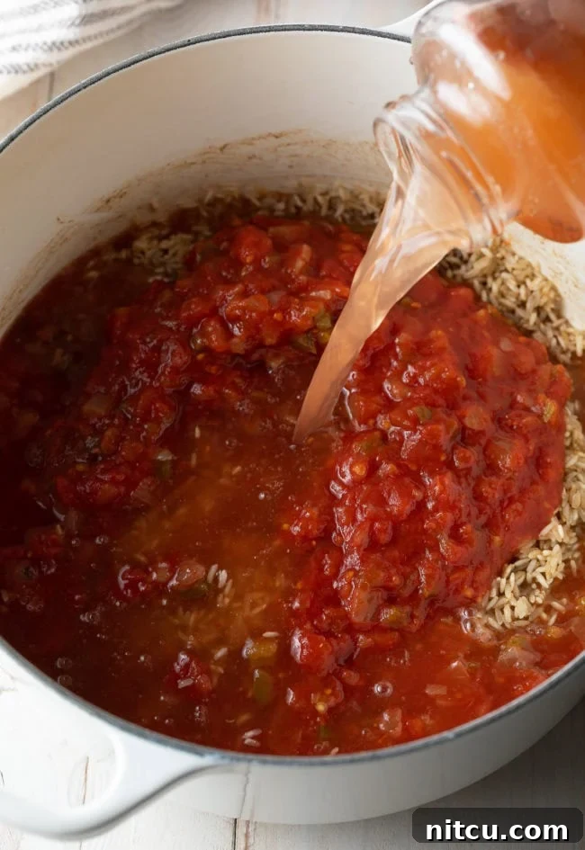Water being poured from the salsa jar into the pot of rice and salsa, illustrating how to get all the residual flavor and ensure proper liquid measurement. This step is part of the 'incorporate the salsa and liquid' instruction, ensuring all ingredients are combined for cooking.