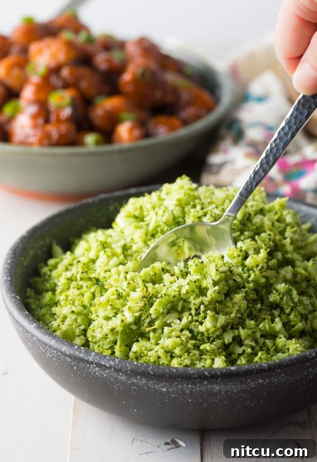 Close-up side view of a serving of roasted broccoli rice in a black dish, highlighting its delightful texture