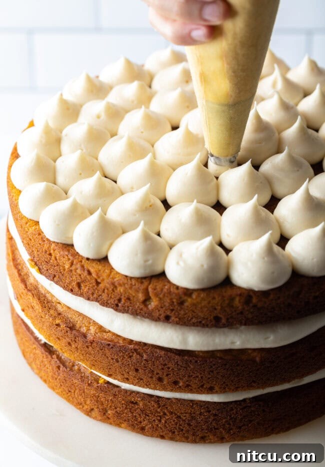 Hand piping frosting onto top layer of cake. 