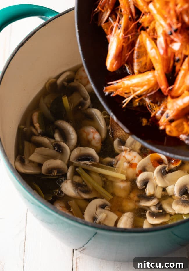 Cooked shrimp are added to a pot of Tom Yum soup, joining mushrooms and fragrant lemongrass, just before serving.