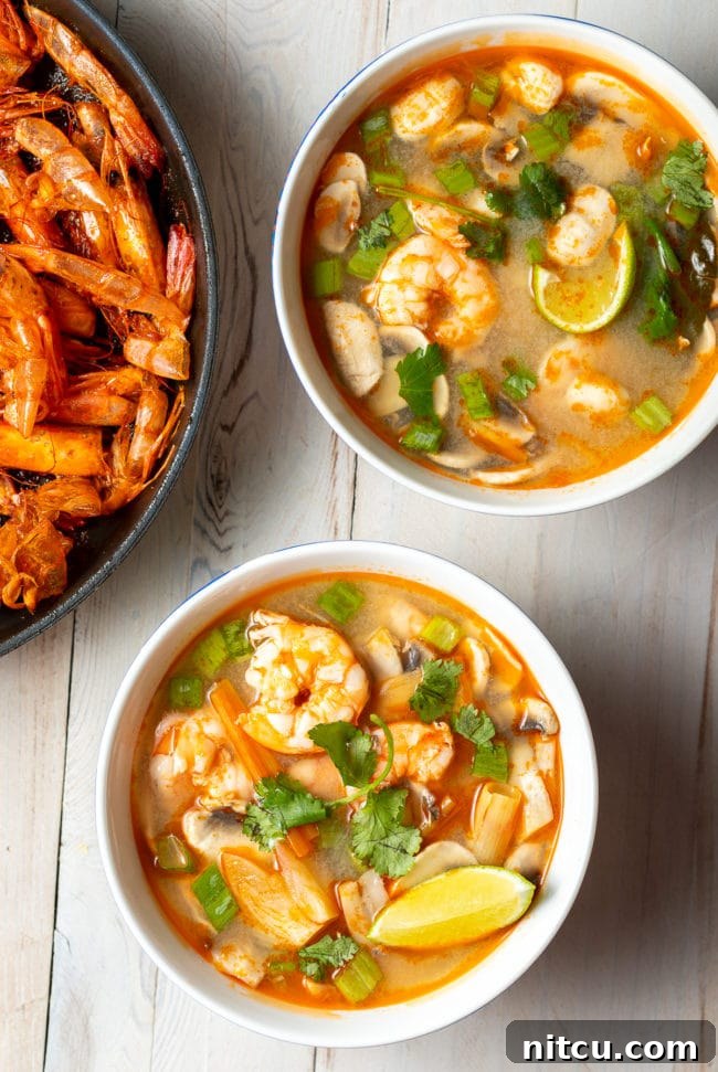 An overhead shot showcasing two bowls of beautifully plated shrimp Tom Yum soup, ready to be enjoyed.