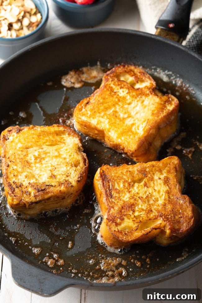 3 pieces of pain perdu on a hot skillet.