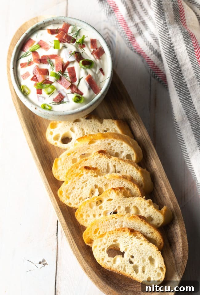 Platter of toasted crostini and a bowl of chipped beef dip. 