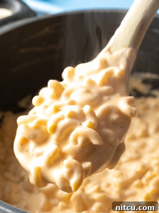 Wooden spoon full of this stovetop Best Homemade Mac and Cheese (with Cream Cheese)