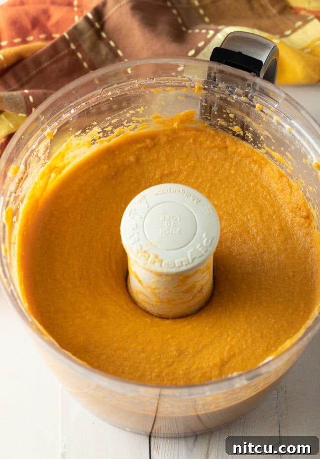A bowl of creamy sweet potato pie filling, perfectly spiced and smooth, showcasing its readiness to be poured into the pie crust.