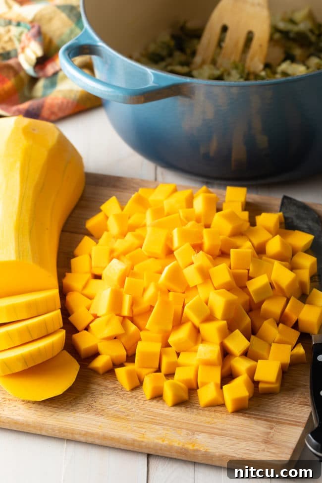 Freshly peeled and diced butternut squash cubes on a wooden cutting board, ready for cooking.