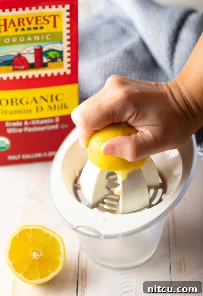 A hand expertly using a lemon juicer to extract fresh lemon juice into a bowl.