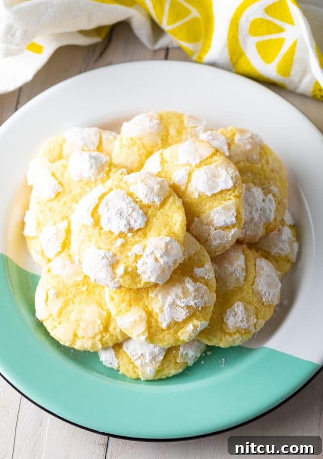 A stunning overhead shot showcasing a plate filled with perfectly stacked, powdery Lemon Crinkle Cookies, ready to be enjoyed.