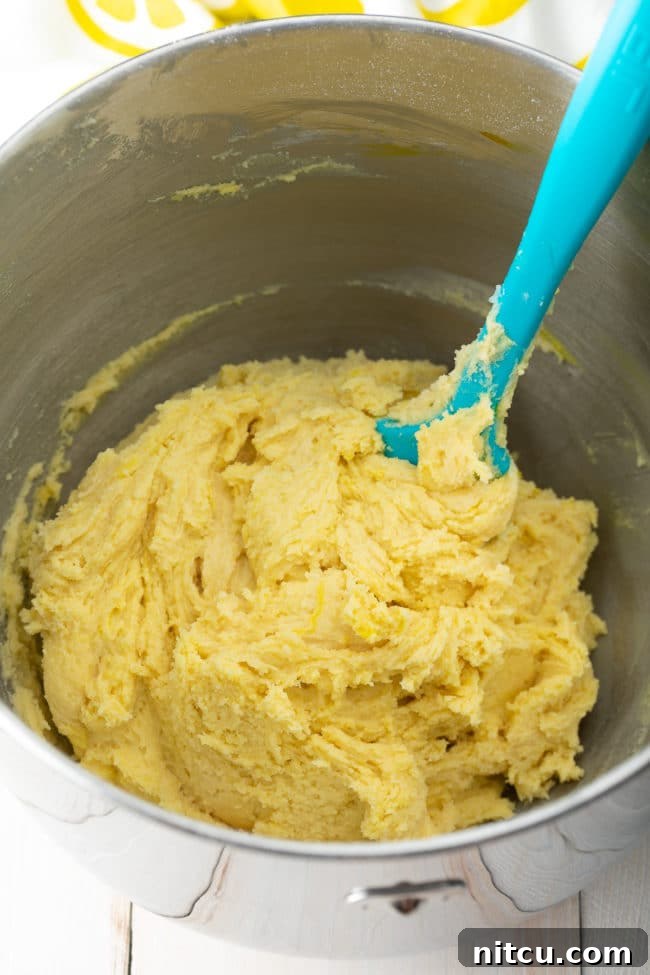 A mixing bowl filled with freshly prepared Lemon Crinkle Cookie dough, showing its smooth, yellow consistency.