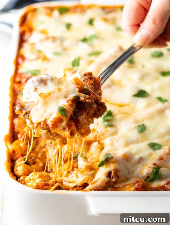 baked ziti with sausage and ricotta spooned up from dish, highlighting the cheesy layers