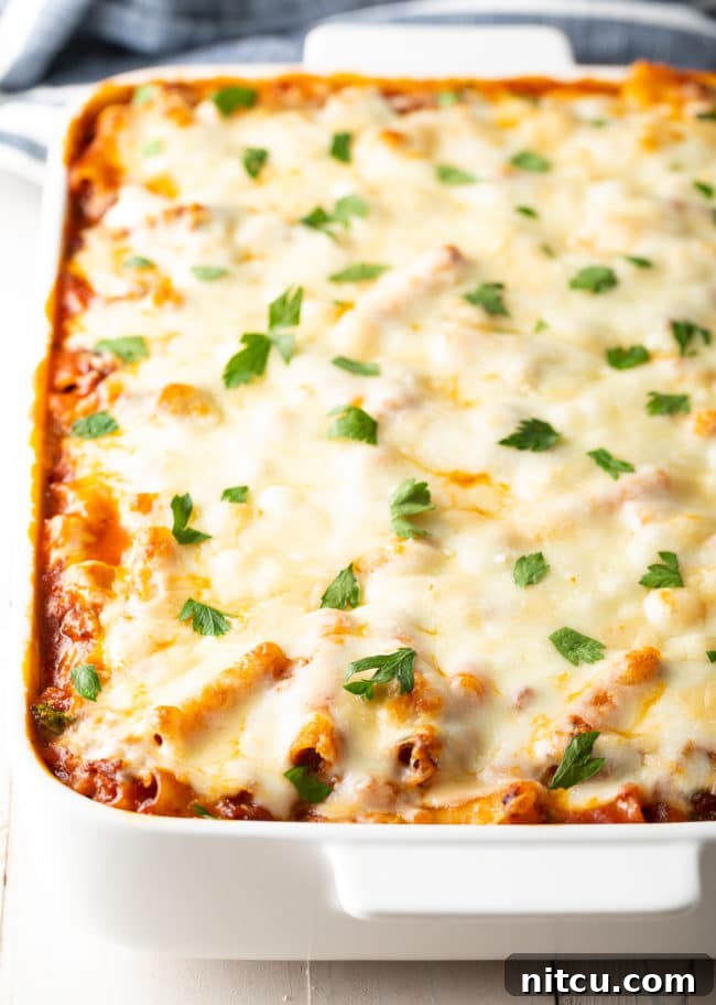 Baked ziti with Italian sausage baking in a casserole dish, showing the no-boil pasta