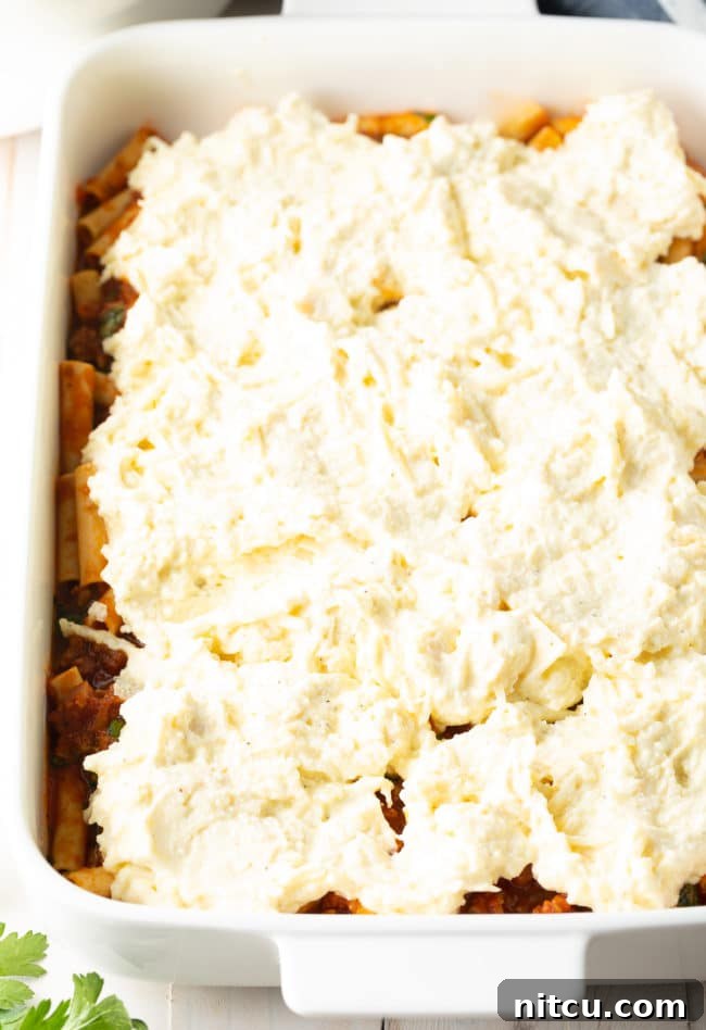 Ricotta Filling on top of ziti - Baked Ziti with Sausage Recipe, showing the layering process