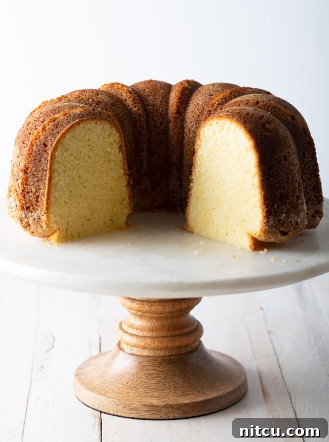 A side view of a beautifully sliced bundt cake on a cake stand, revealing its moist, tight crumb and tender interior texture.