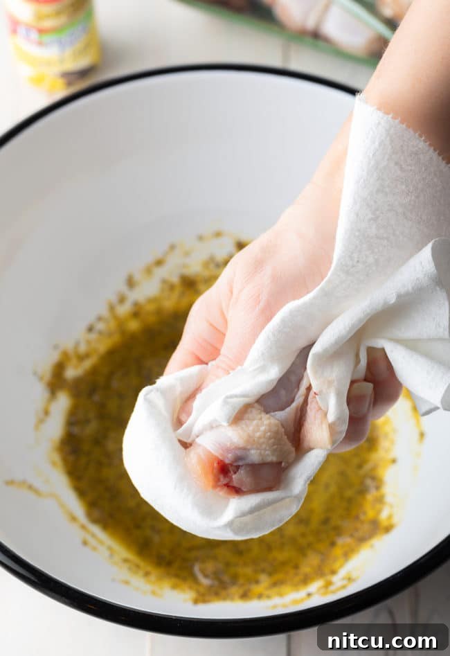 Patting chicken wings dry with paper towels