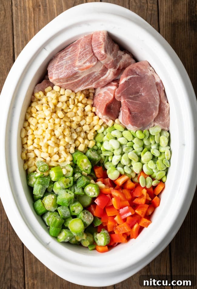 Ingredients for Brunswick stew piled in the slow cooker before being cooked, showcasing fresh vegetables and meat.