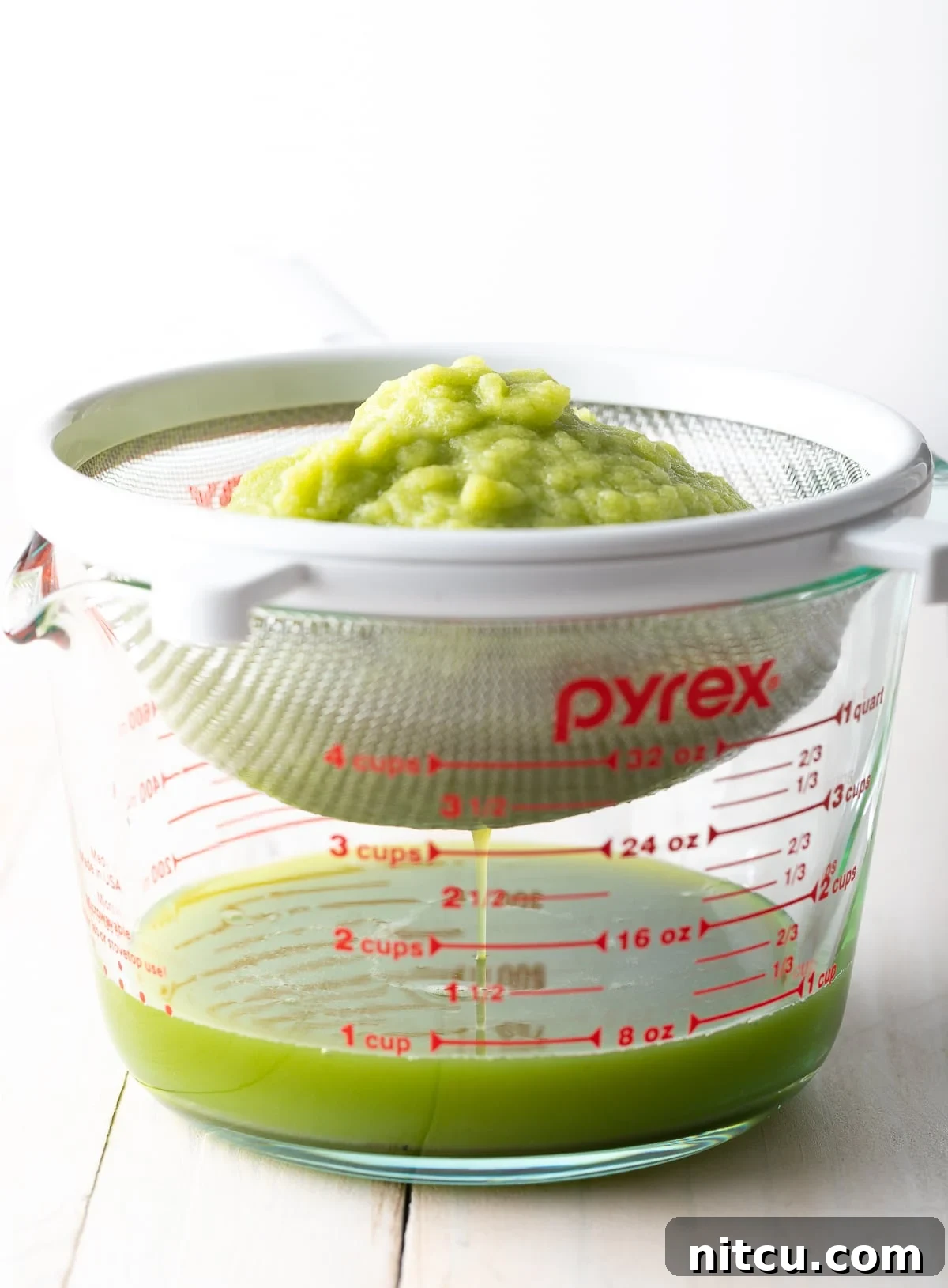 Celery juice being drained into a glass. 